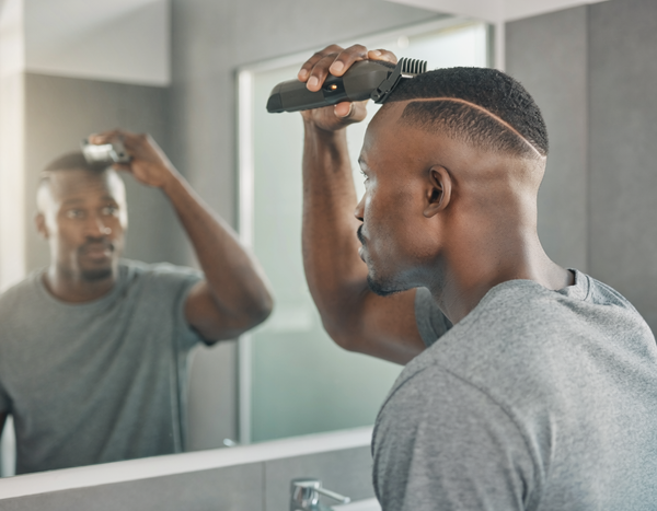 Man knipt zichzelf een buzzcut met een draadloze tondeuse en opzetkam